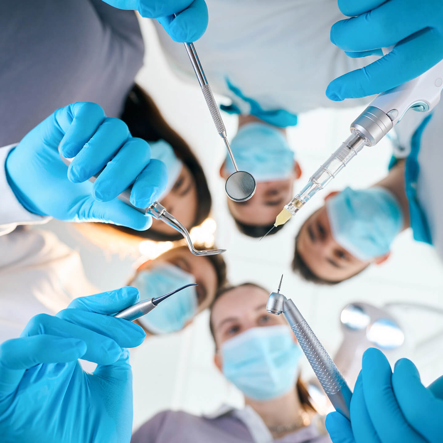 Four dentists holding dental tools together in a star-like pattern, symbolizing teamwork and innovation in dentistry.
